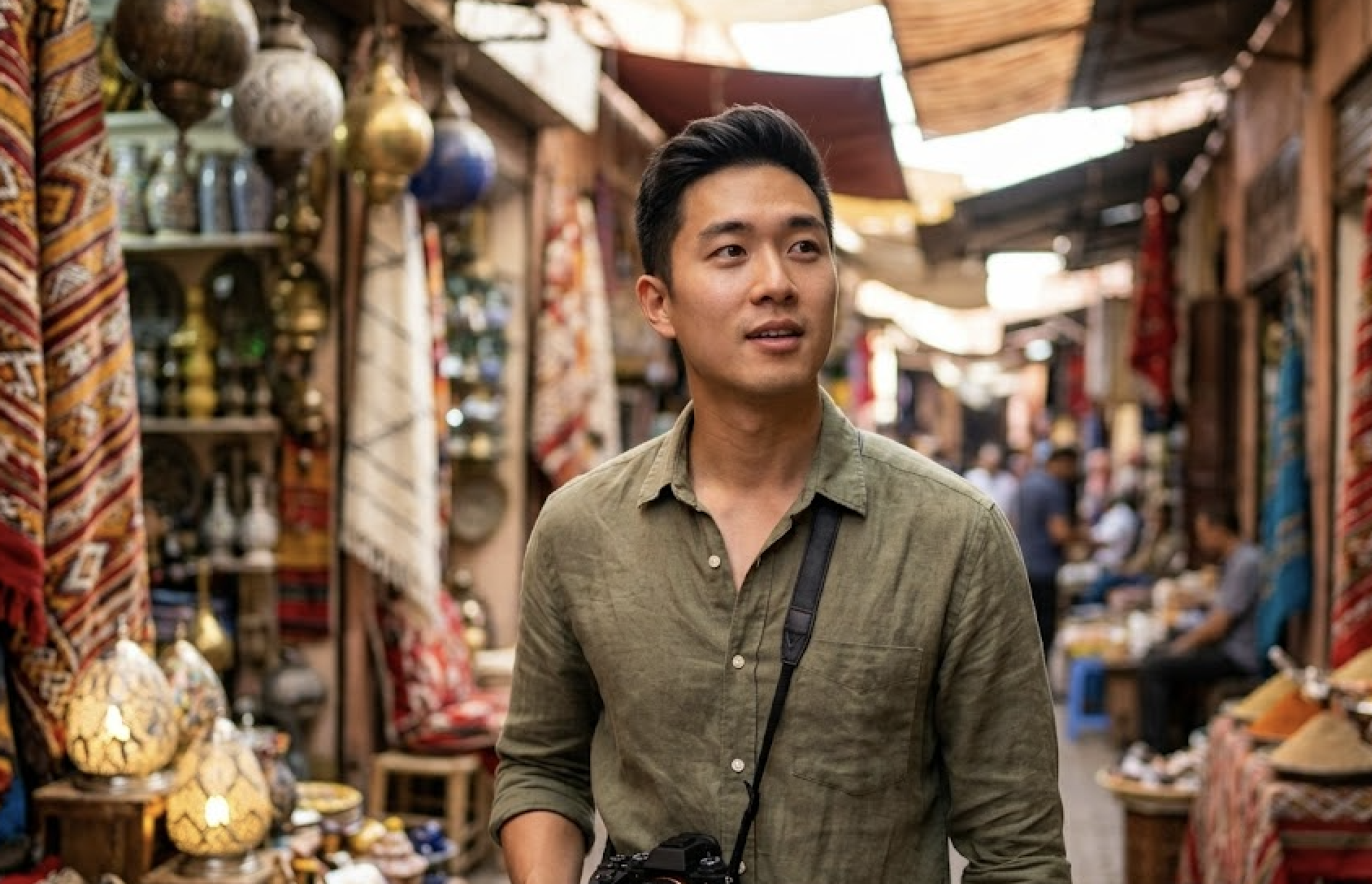 A man in a green shirt with a camera explores a bustling market.