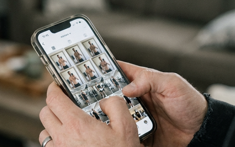 Hands hold a smartphone displaying many fitness-related photos in a grid.