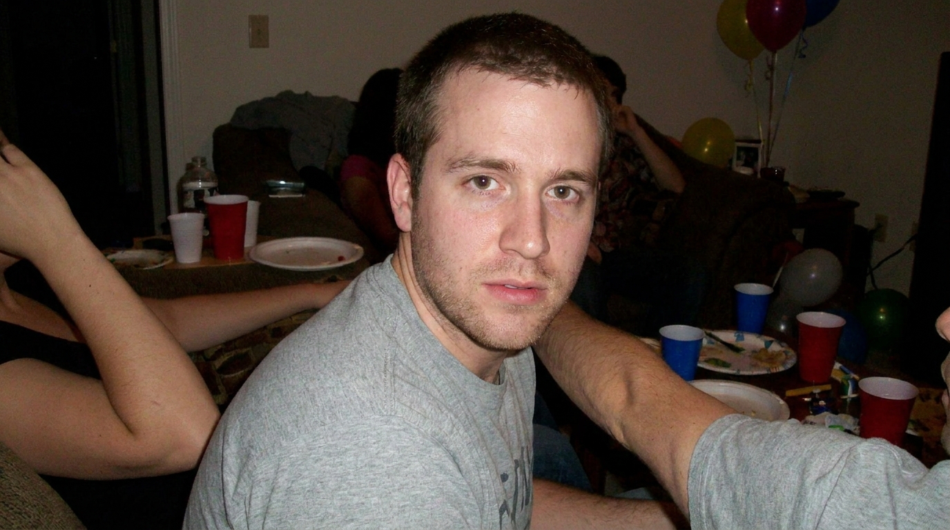 A man with short hair and stubble stares intently at the camera.